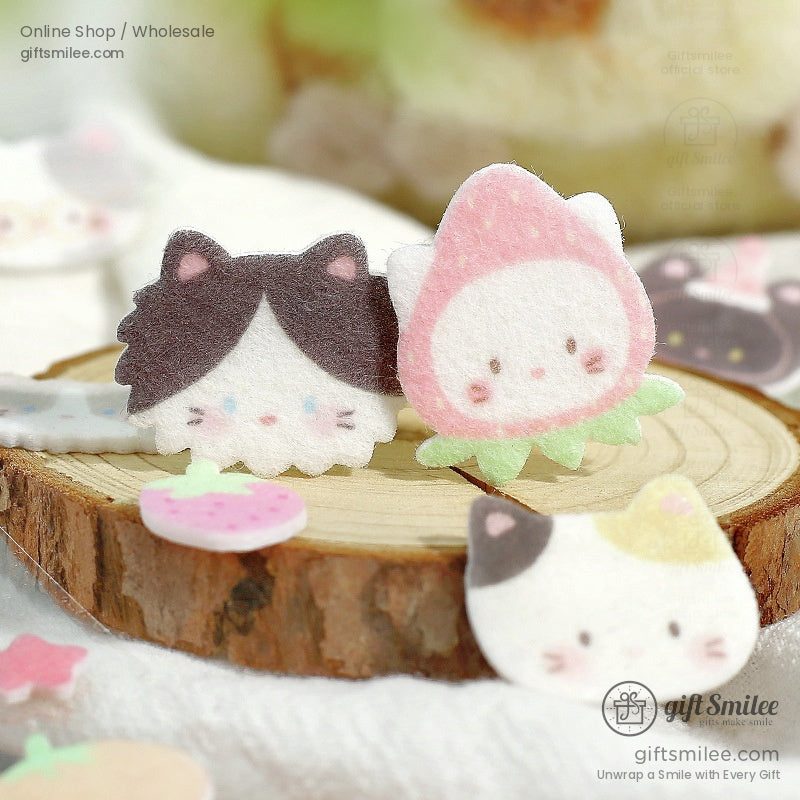 Cat and strawberry-themed puffy stickers displayed on a wooden slice with pastel accents