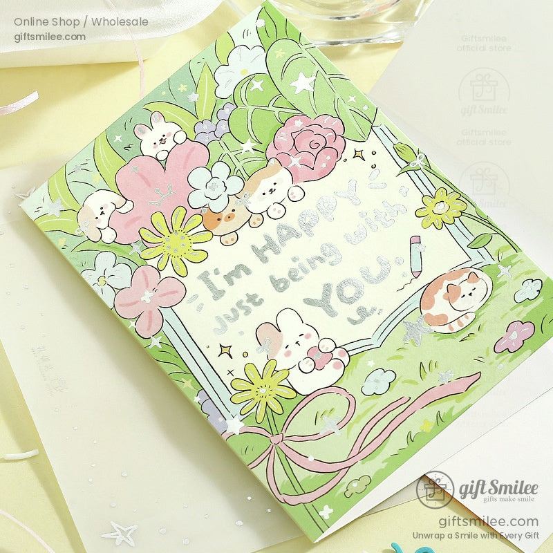 Pastel green greeting card with cartoon animals pink and yellow flowers and handwritten message in playful font