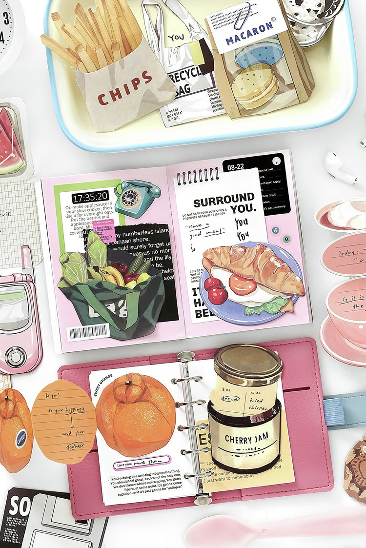 Colorful flat lay of a pink planner cherry jam jar fresh orange croissant plate fries and stationery items