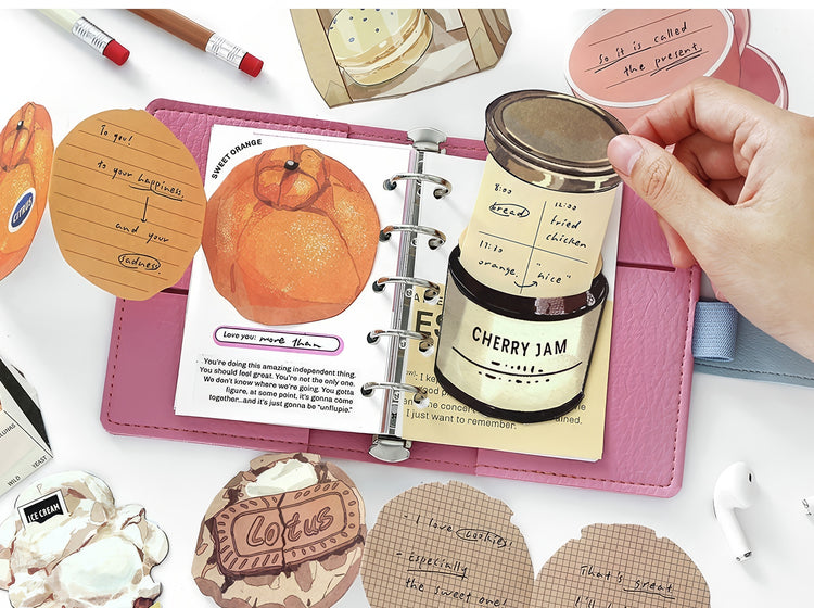 Pink leather journal with illustrated fruitthemed pages cherry jam label insert and decorative vintagestyle stickers