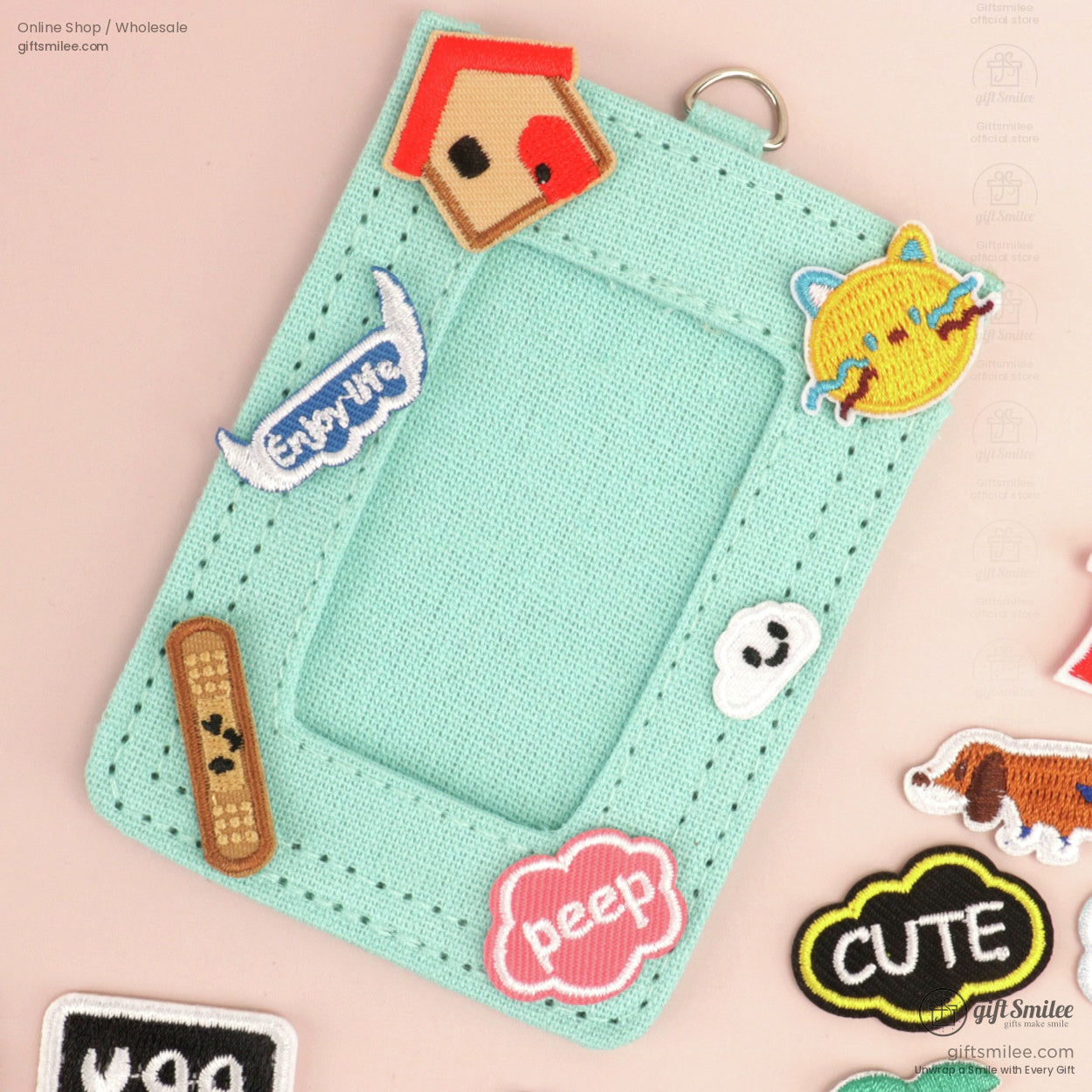 Mint green fabric cardholder with embroidered patches including a birdhouse sun and speech bubbles in playful colors