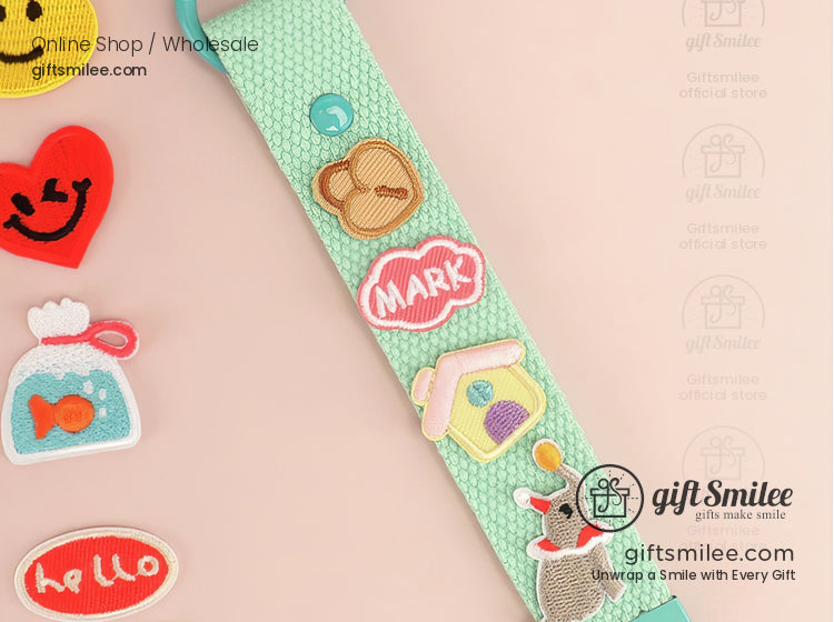 Mint green woven keychain with colorful embroidered patches including an elephant fishbowl and playful icons