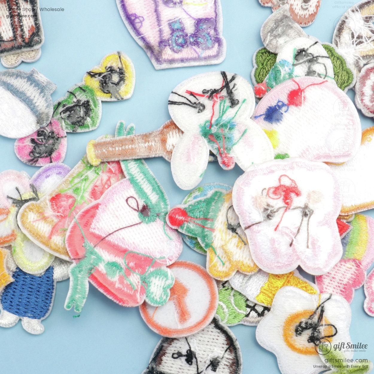 Assorted colorful embroidered fabric patches with playful designs featuring animals and objects on a light blue background