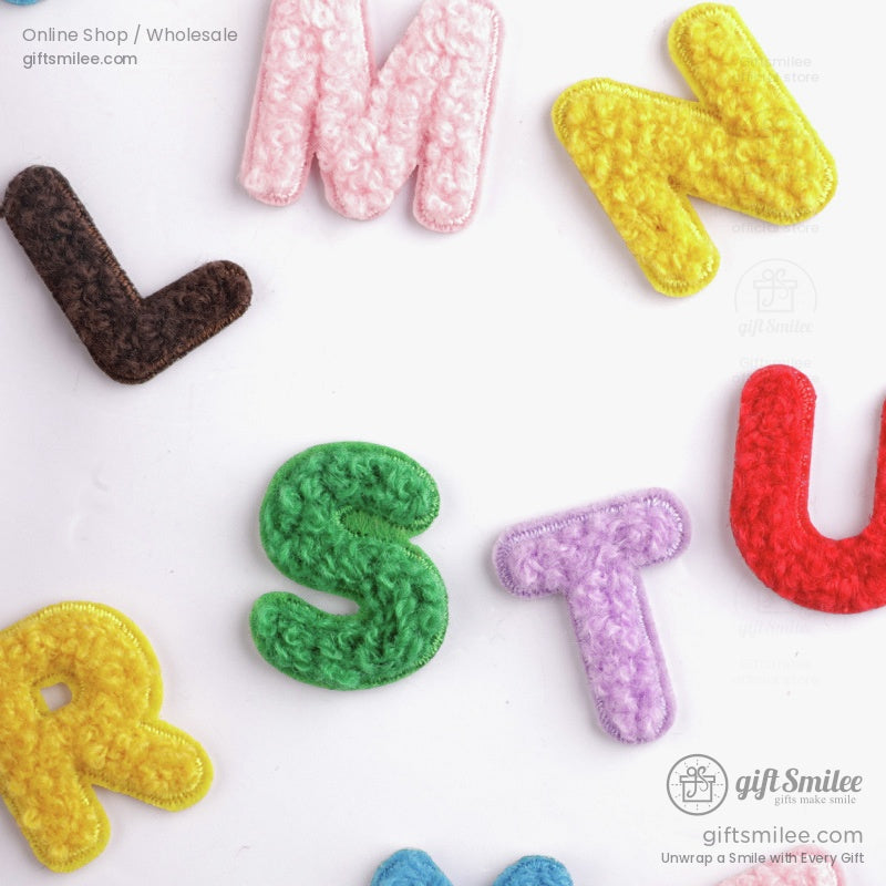 Multicolored chenille fabric letters in green pink yellow red brown and purple on a white background