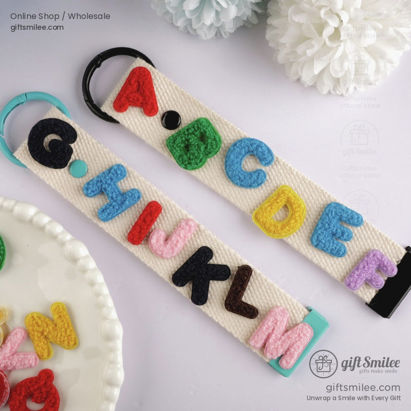 Cream canvas keychains with colorful 3D embroidered alphabet letters and teal and black metal key rings