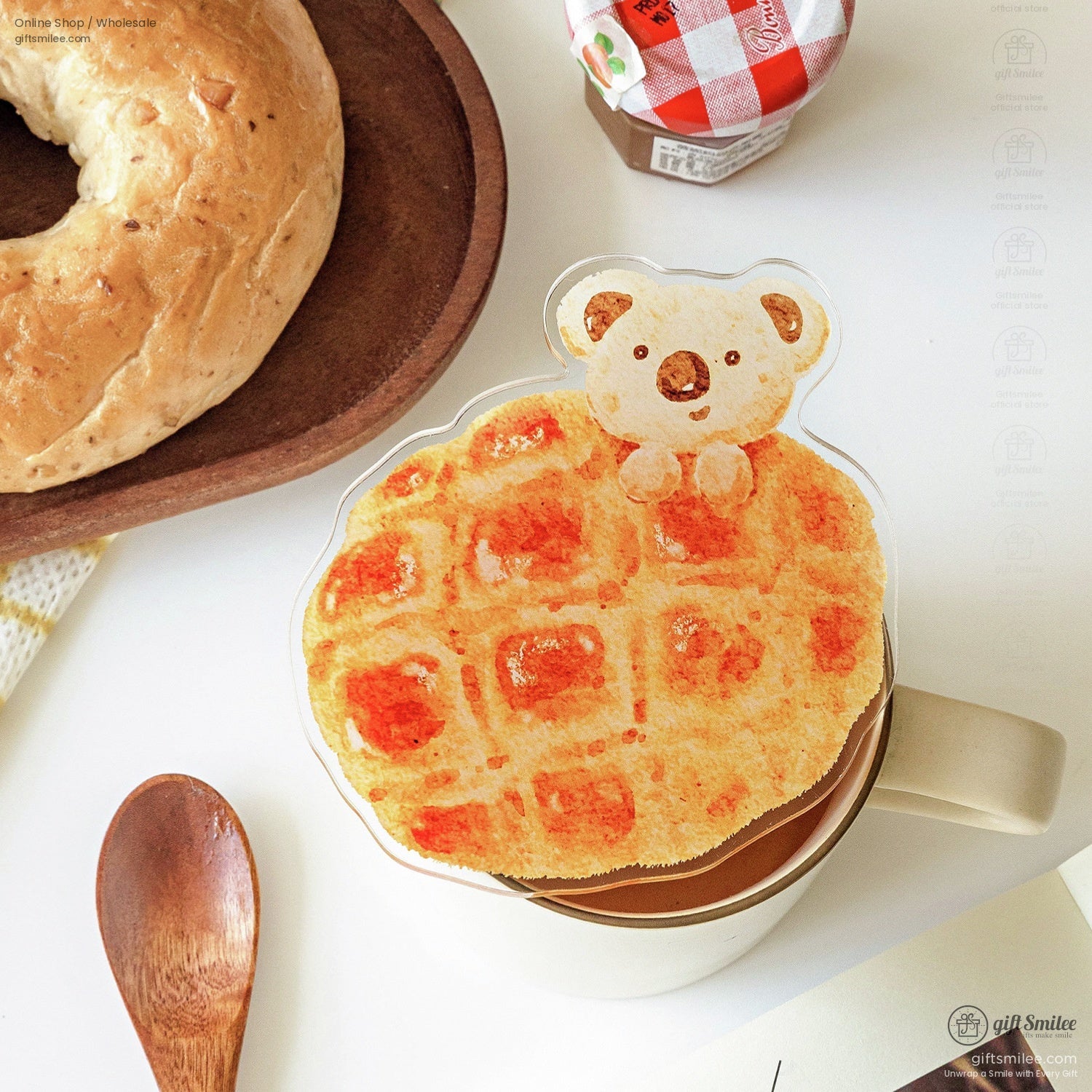 Waffle-shaped coaster with a bear design placed on a coffee mug and next to a bagel
