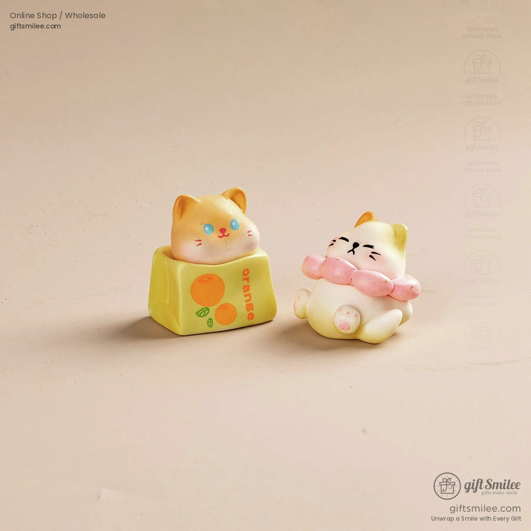 Two pastel cat figurines one on a yellow orangethemed block and the other with a pink ruffled collar playful design
