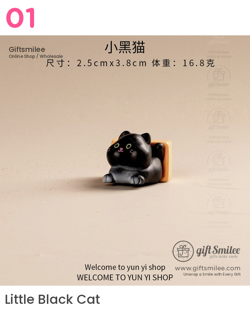 Black ceramic cat figurine with yellowgreen eyes pink nose and an orange rectangular cushion on a beige surface