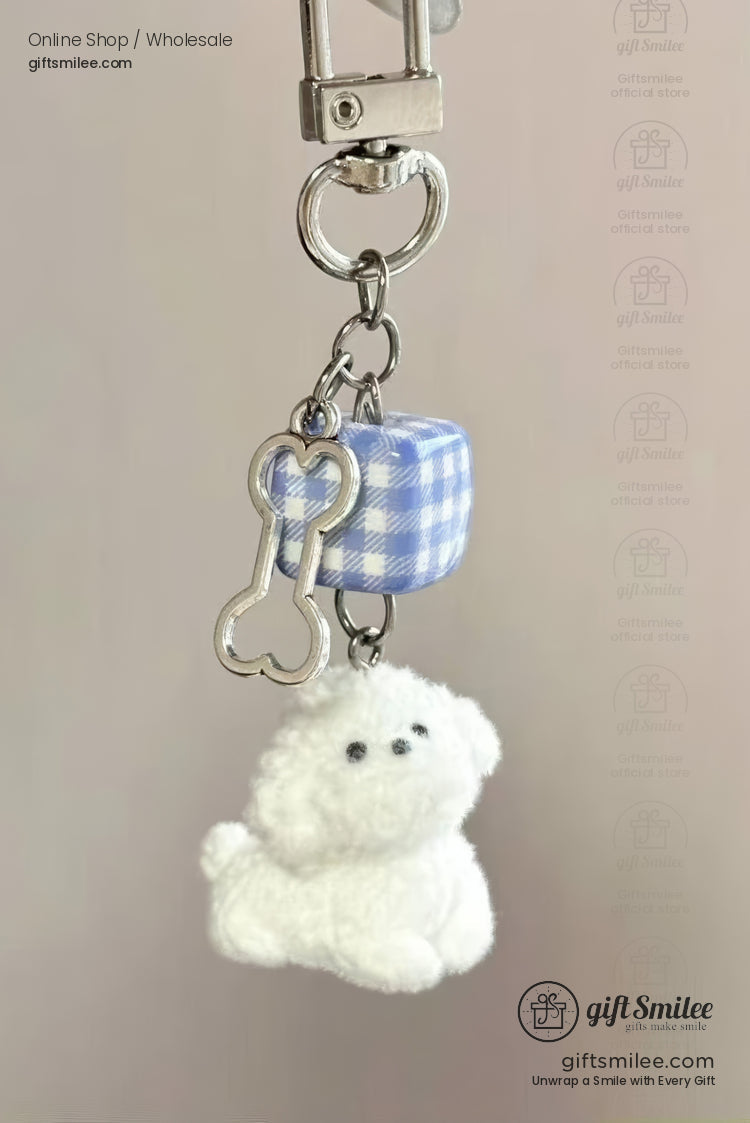 Plush white dog keychain with a silver metal bone charm and blue gingham cube attached to a sturdy clip