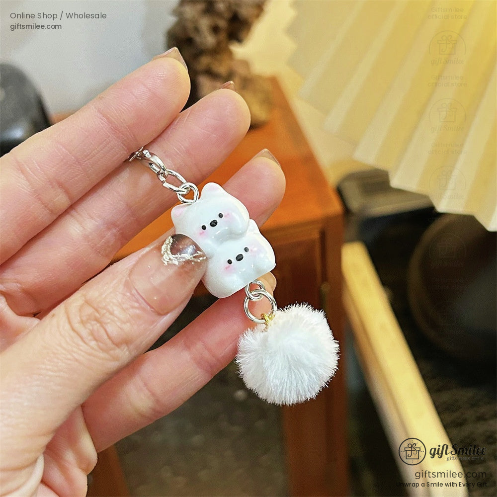 White ceramic bear keychain with pink blush details and a fluffy white pompom charm on a silver metal chain