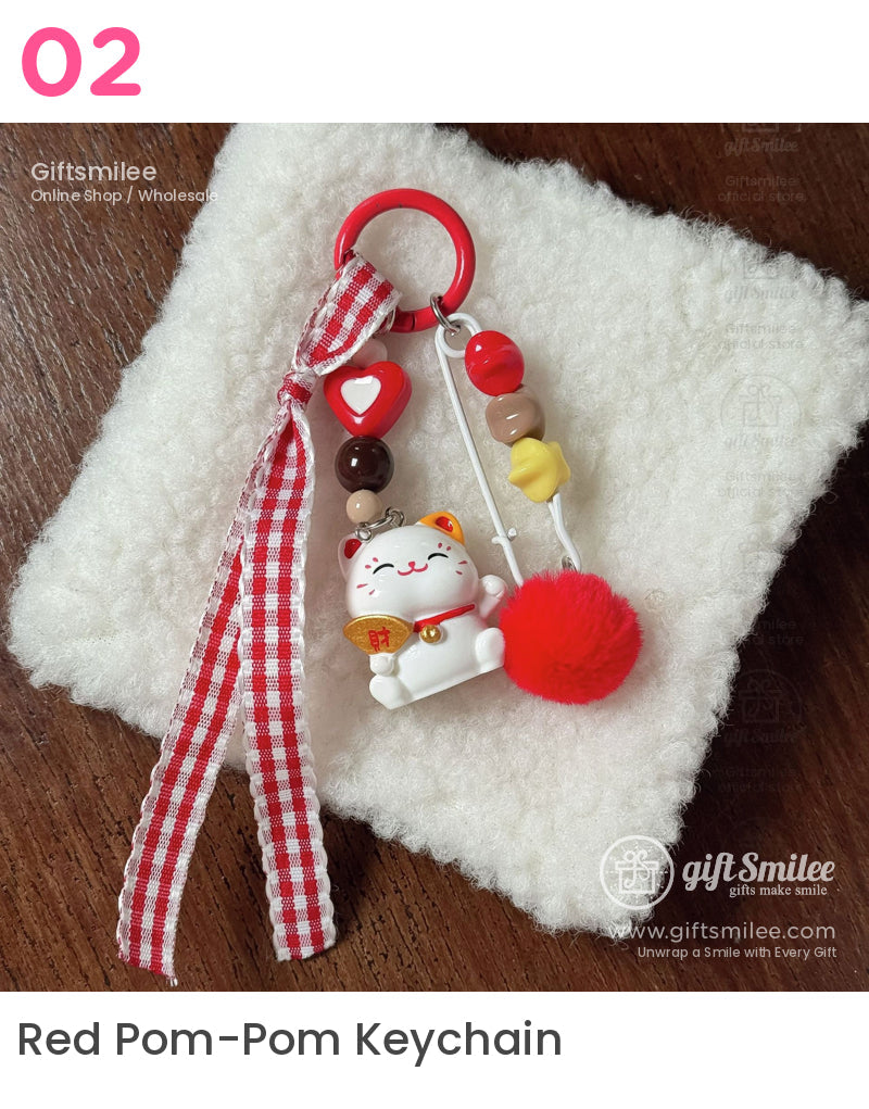 Red and white keychain with a lucky cat charm gingham ribbon colorful beads and a fluffy pompom on soft fabric