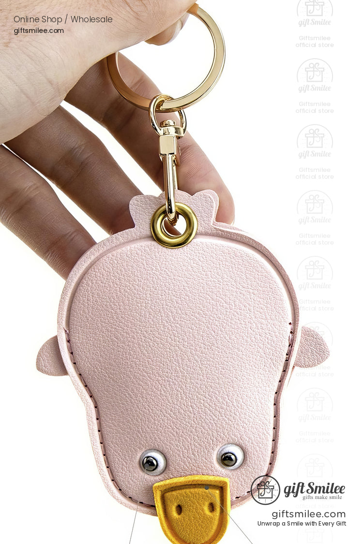 Pastel pink leather duckshaped keychain with golden keyring stitched edges googly eyes and a yellow beak