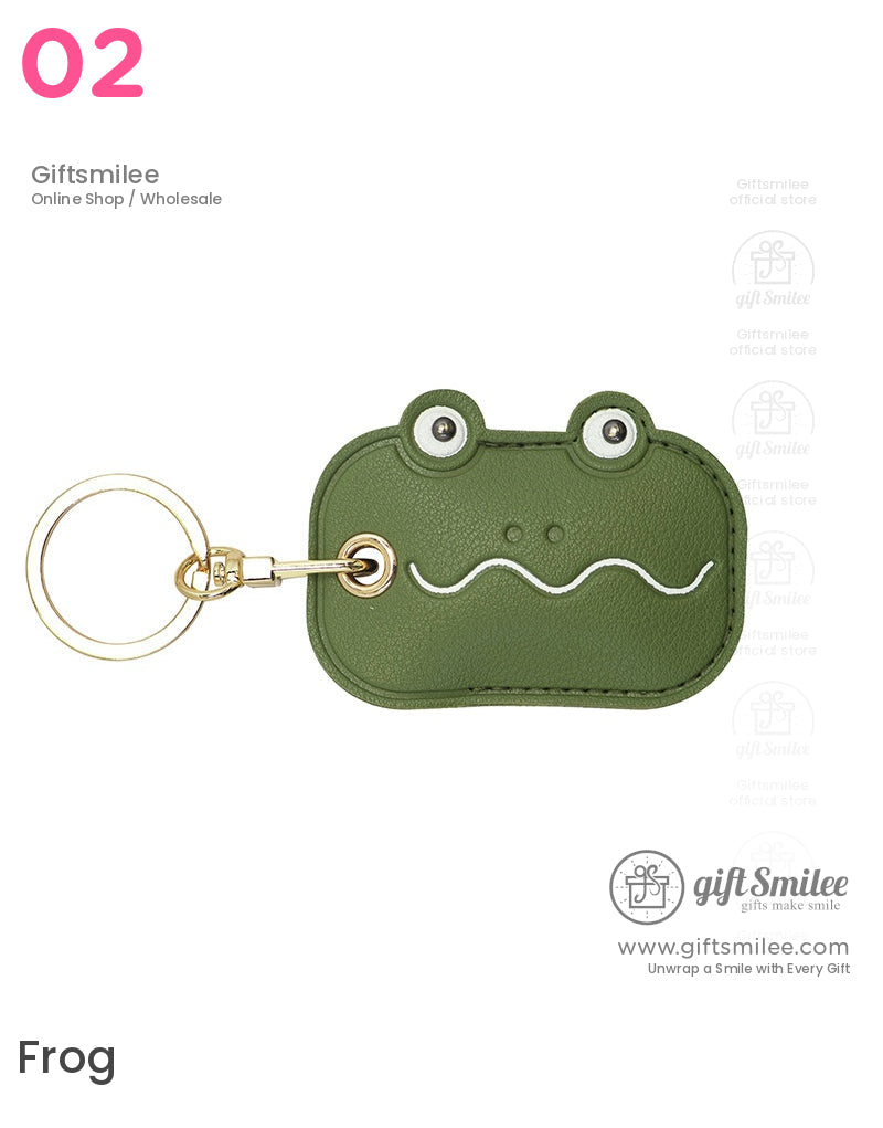 Green leather keychain shaped like a frog face with stitched details silver eyes wavy mouth and gold keyring