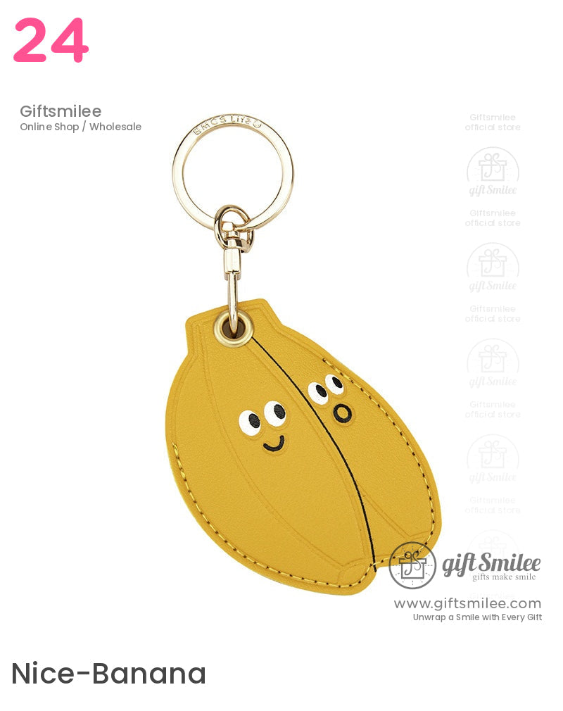 Yellow leather bananashaped keychain with playful cartoon faces and a goldtone metal keyring attachment