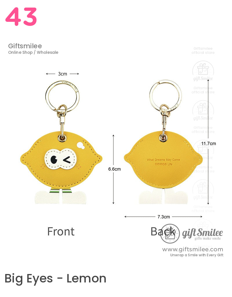 Yellow lemonshaped leather keychain with winking face design gold ring clasp and playful white legs charm