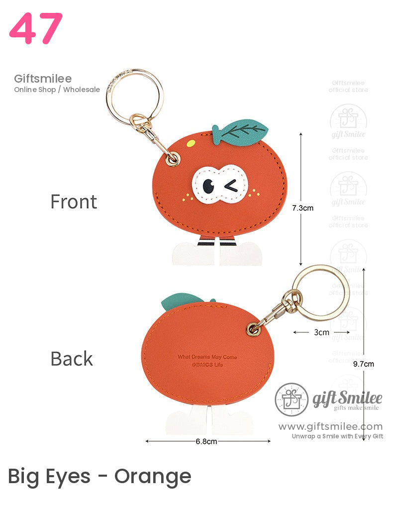 Orange faux leather keychain shaped like a winking fruit with green leaf detail gold ring and playful white legs