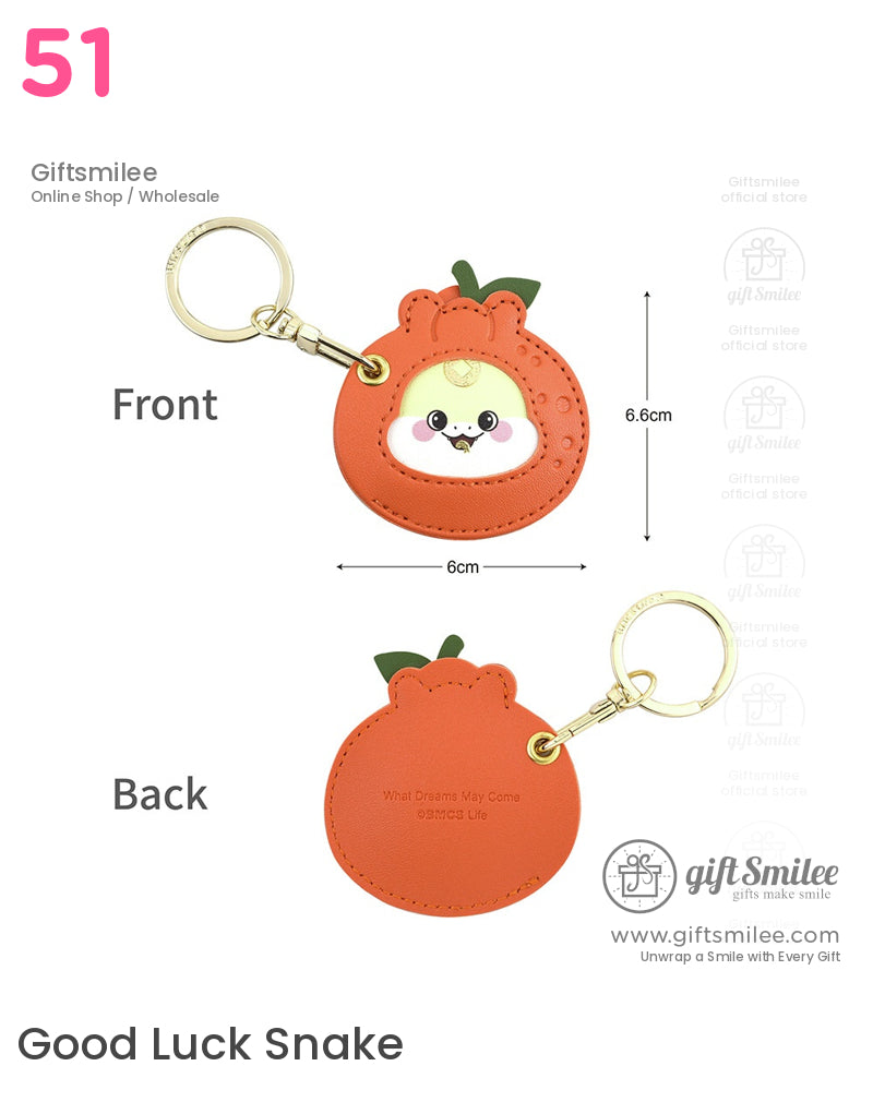 Orange faux leather keychain shaped like a fruit with a cute animal face insert goldtone clip and green leaf accents
