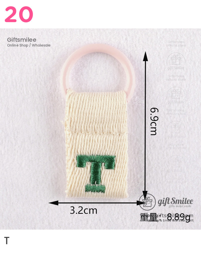 Beige woven fabric keyring with green embroidered T and a soft pink circular loop measuring 69cm by 32cm