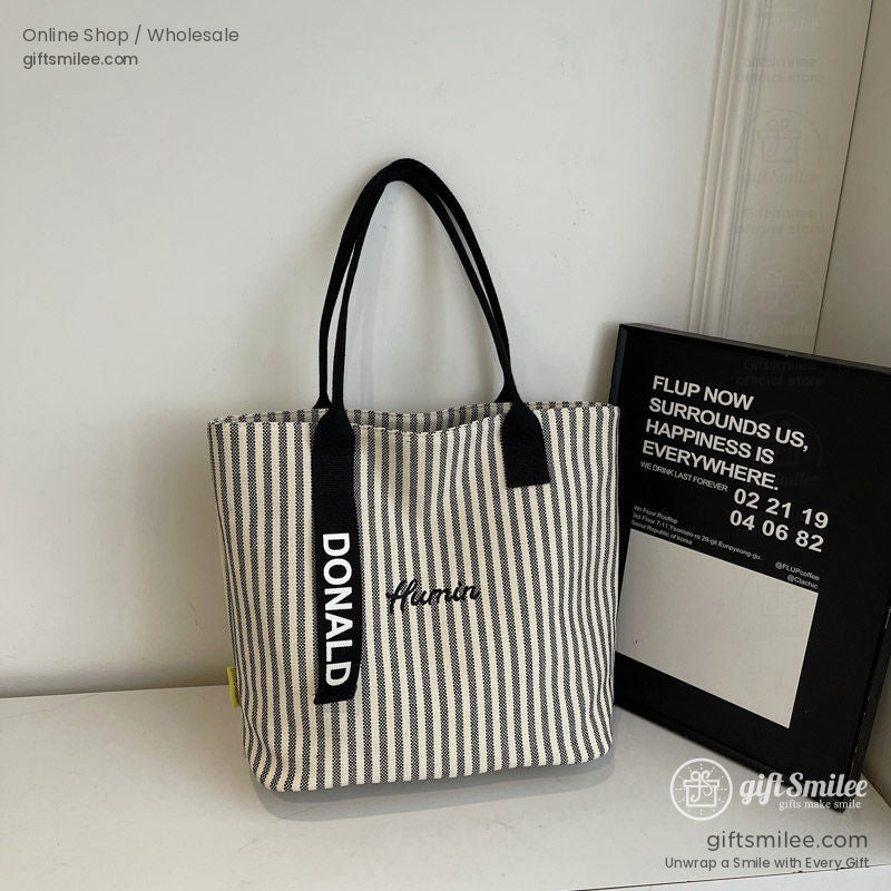 Beige and black striped canvas tote bag with embroidered Human black handles and a Donald strap accent