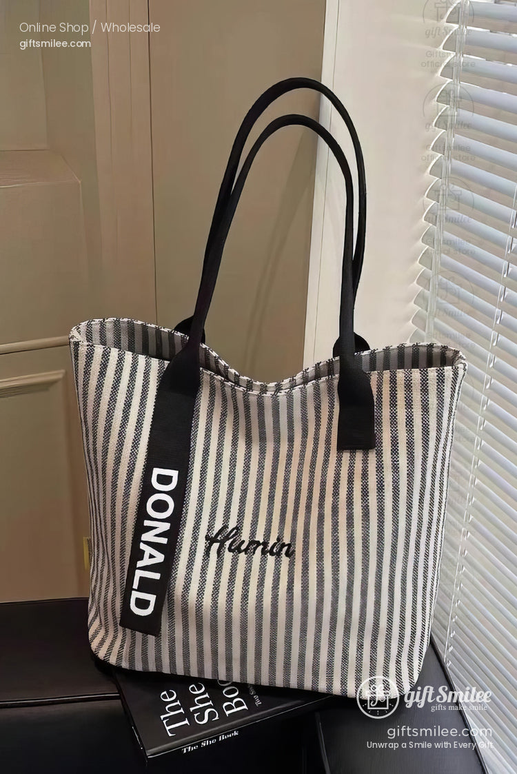 Gray and white striped canvas tote bag with black handles embroidered text and a bold DONALD strap accent