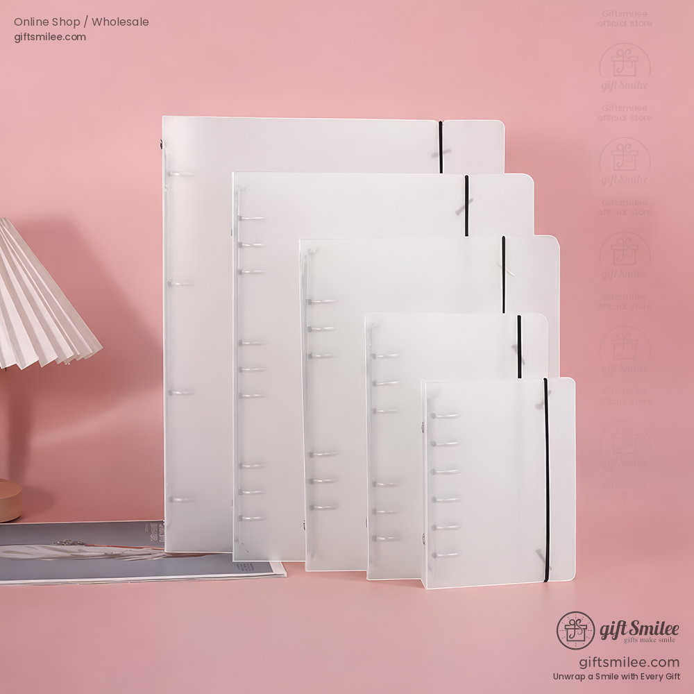 Translucent white plastic notebooks in various sizes with black elastic closures displayed against a pink background