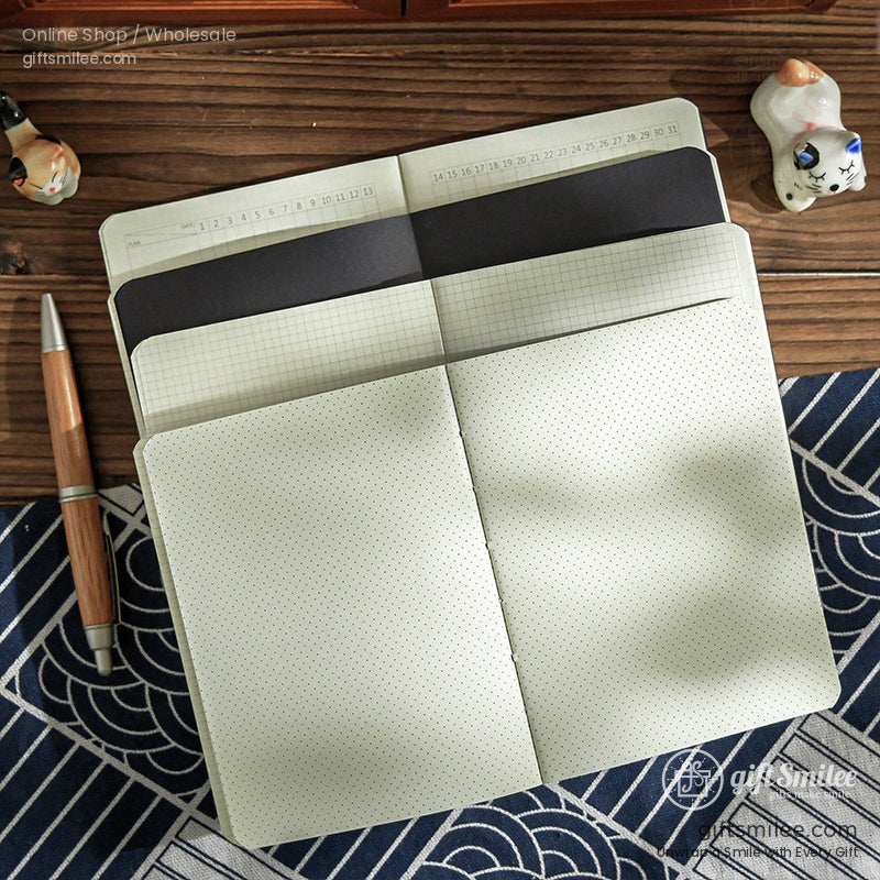 Open beige notebook with dotted grid and black pages on a wooden table paired with a wooden pen and decorative accents
