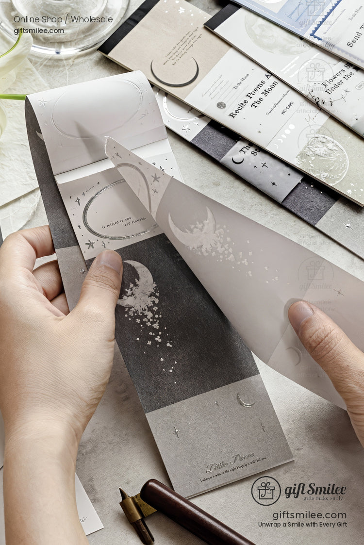 Hands peeling a celestial-themed washi sticker sheet with moon and star designs from GiftSmilee stationery set on a desk.