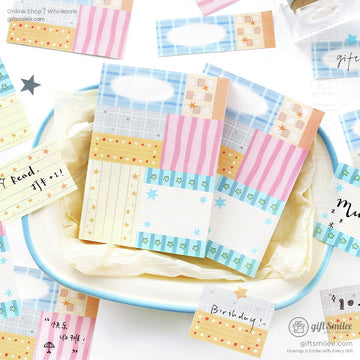 Pastelcolored memo pads with grid stripe and star patterns in blue pink and yellow tones arranged on a white tray