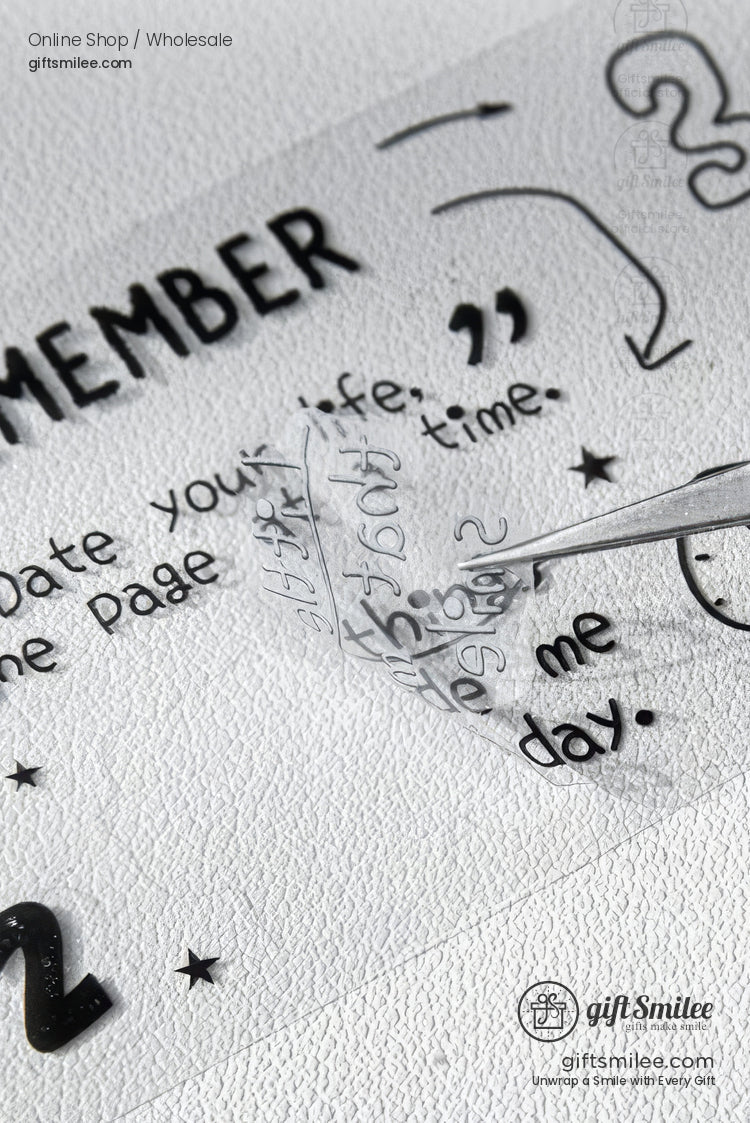 Clear transfer tape lifting black vinyl letters during application on a textured white surface with hand-drawn text and stars.