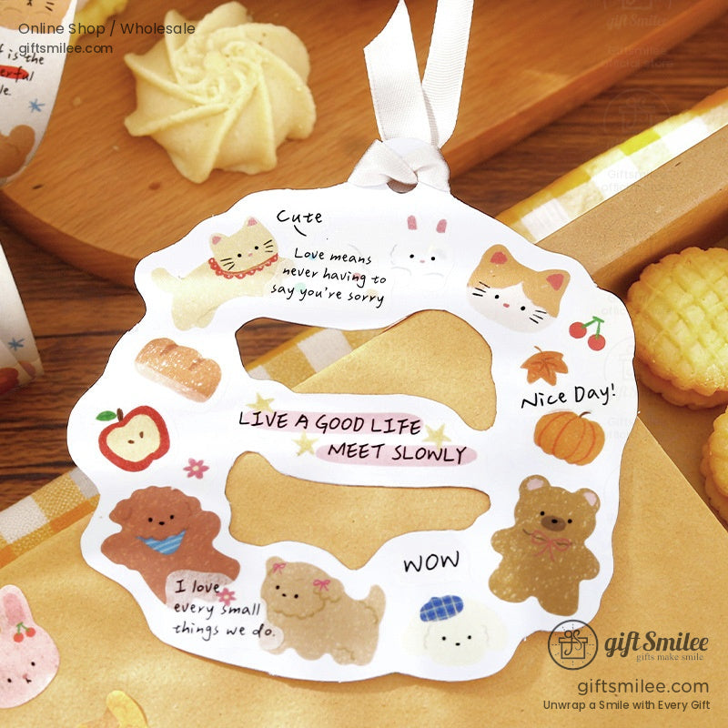 White diecut paper tag with cute animal illustrations motivational text and ribbon placed on a wooden table with cookies