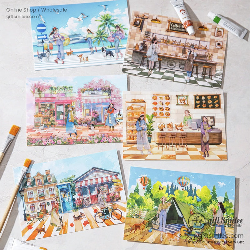 Flat lay of six colorful illustrated postcards with women, pets, cafes, bakeries, and outdoor scenes, displayed on a marble surface with paintbrushes and paint tubes.