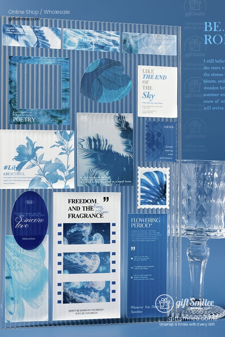 Assorted bluetoned prints with nature motifs layered on a ribbed acrylic panel alongside an ornate crystal glass