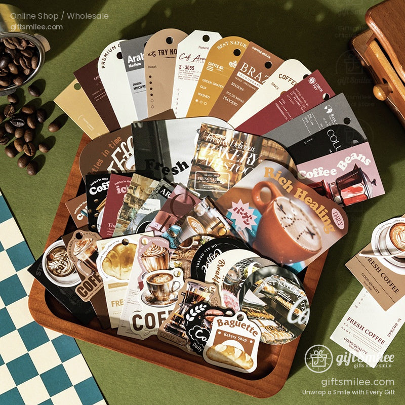 Assorted coffeethemed stickers and tags in warm brown tones displayed in a wooden tray on a green fabric backdrop