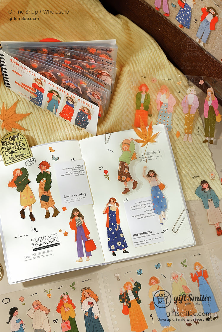 Autumnthemed journal stickers with illustrated characters in cozy outfits displayed on an open notebook and beige fabric