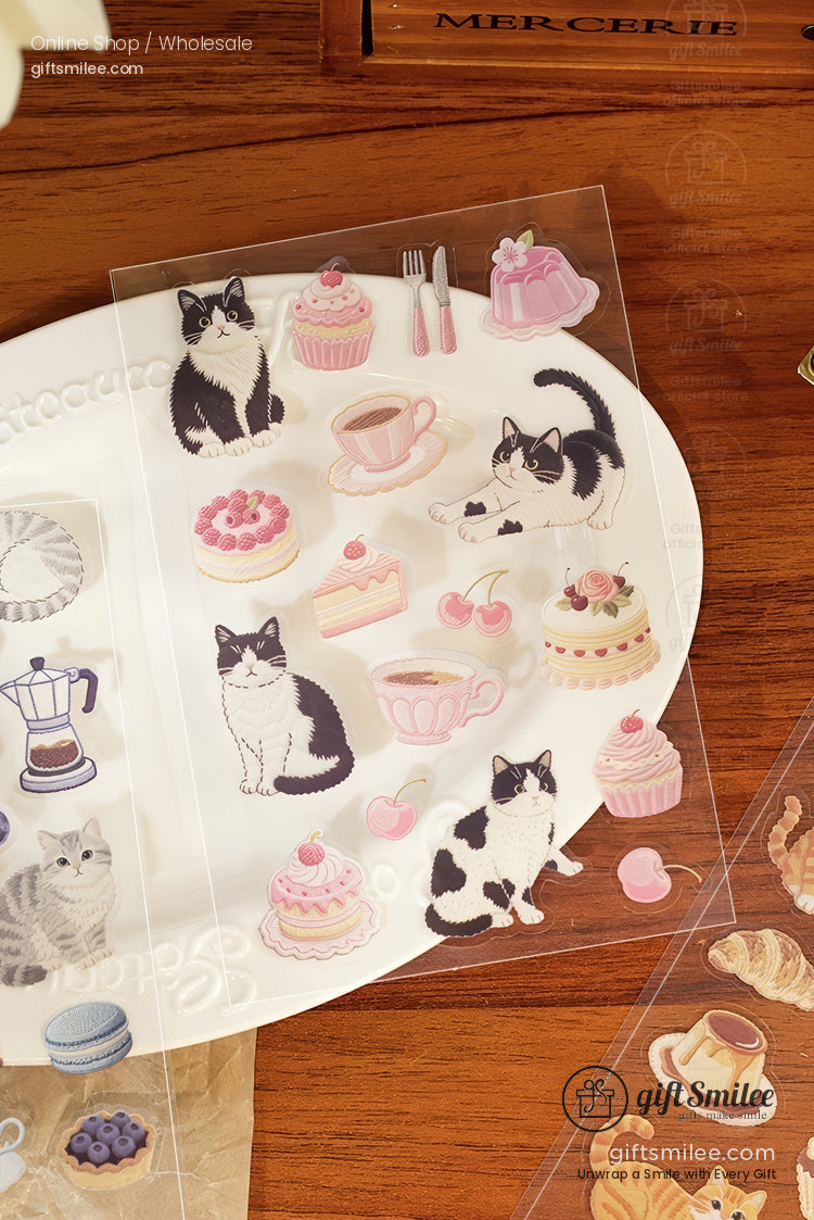 Transparent stickers of blackandwhite cats pink pastries and teacups on a wooden table and white plate