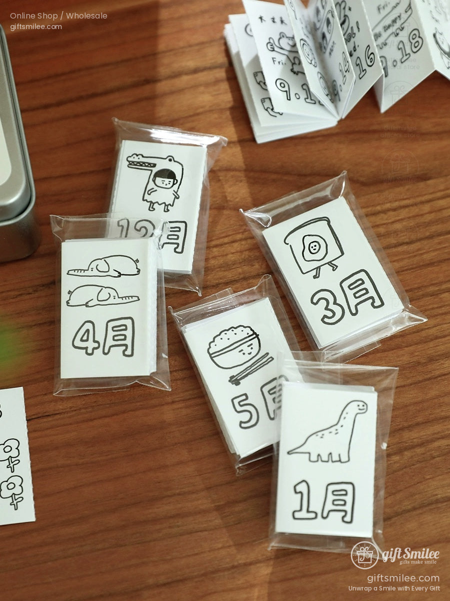 Minimalist blackandwhite sticker packs with handdrawn monthly illustrations in clear plastic sleeves on a wooden surface