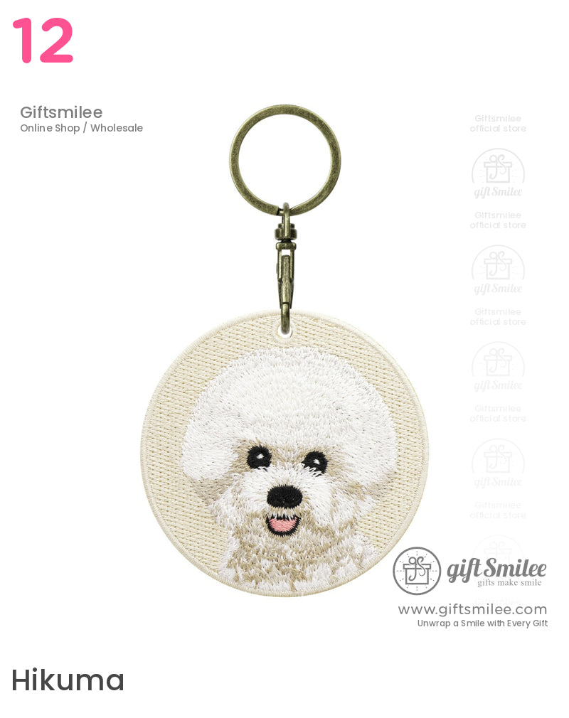 Round beige fabric keychain with an embroidered white fluffy dog face antique brass keyring and textured detailing