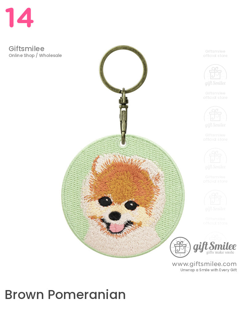 Embroidered Pomeranian face on a light green fabric keychain with antique brasscolored metal clasp and ring