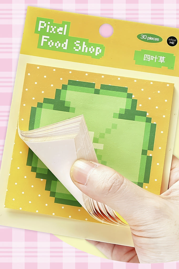 Green pixelated clover sticky notes on yellow polka dot backing with a hand peeling one off 30 pieces pack