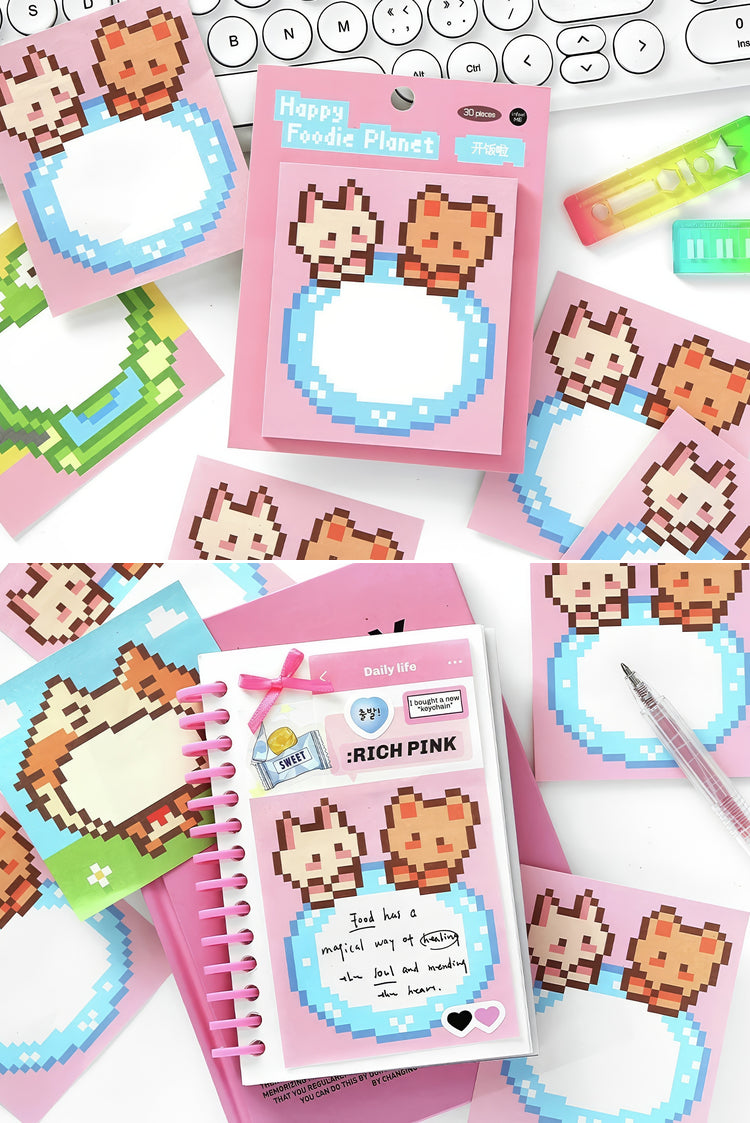 Pink and blue pixel art sticky notes with animal designs paired with a spiral notebook and colorful stationery items
